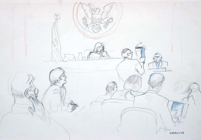 Defense attorney William Bragg questions former Sgt.Pete Ciarabellini while holding up a Makita electric grinder. In the foreground at left is the defense counsel table, and plaintiffs' counsel table is at right.